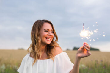 smiling woman holding sparkler and celebrating outdoor